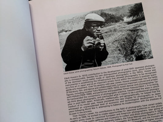 Interior page with a photograph of Eikoh Hosoe holding a camera and introductory text about his career