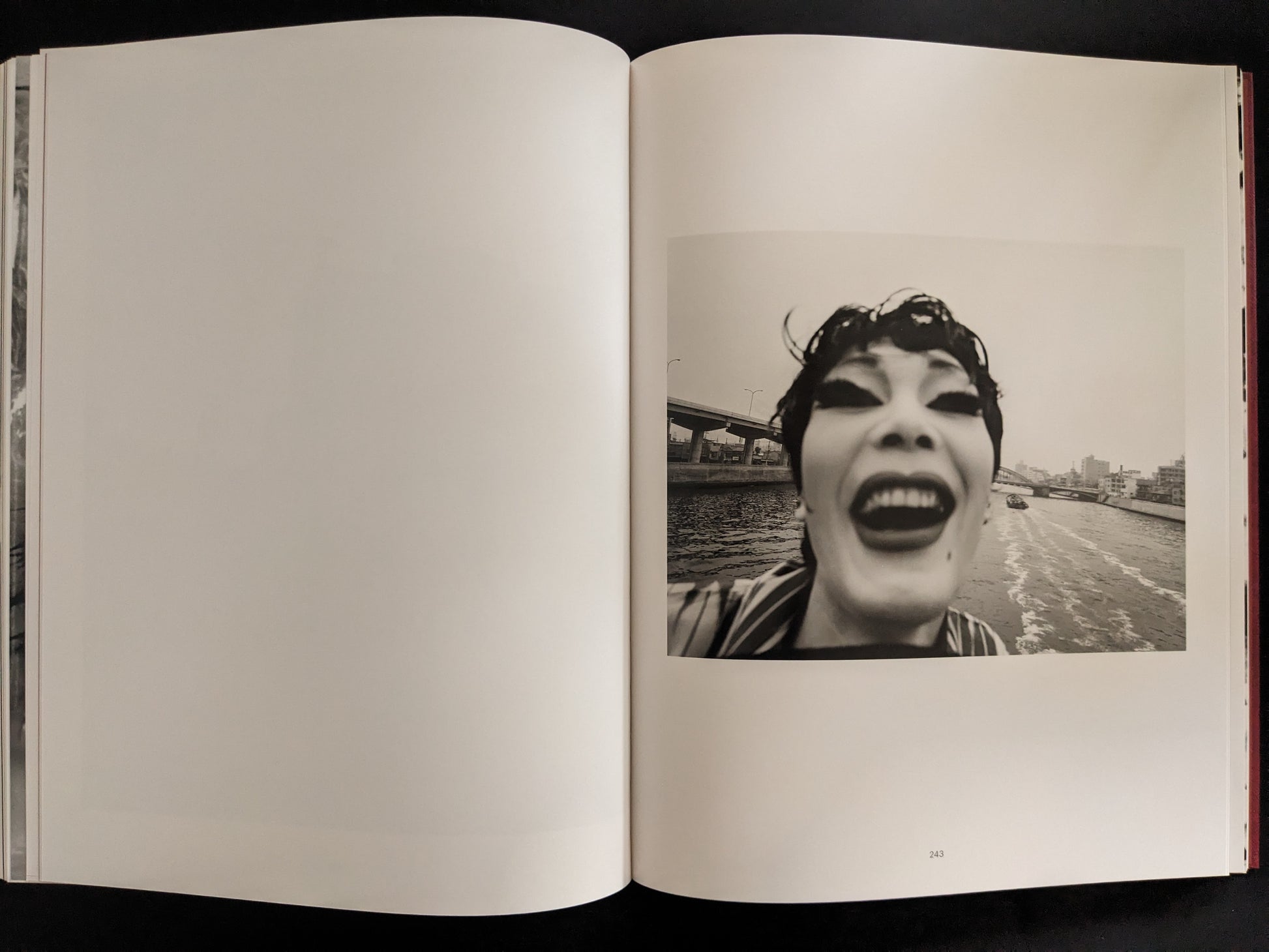 Wide-angle photograph of a performer with exaggerated makeup, smiling at the camera on a river.
