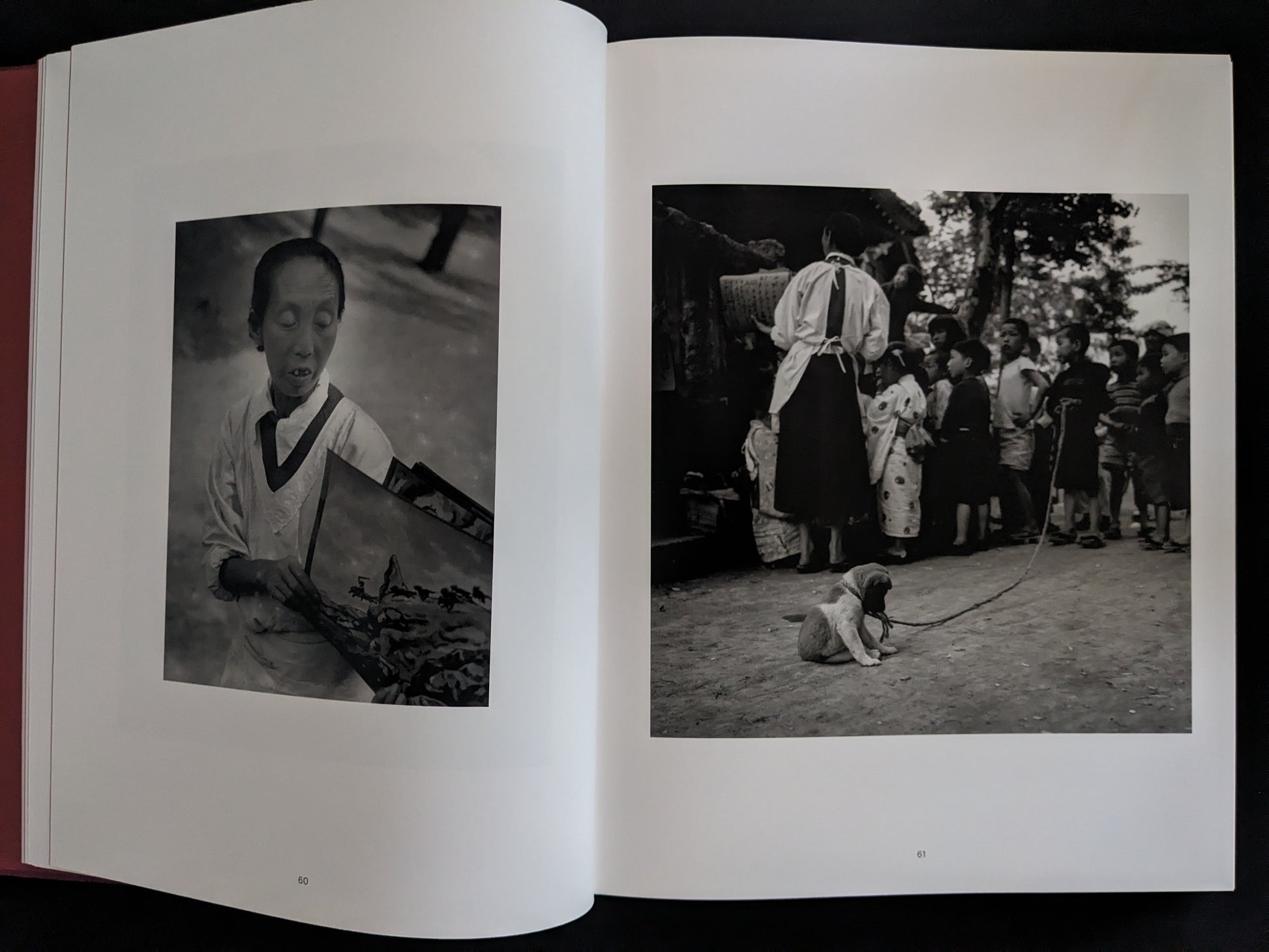 Open book showing black and white photographs of a person and a dog in a traditional setting.