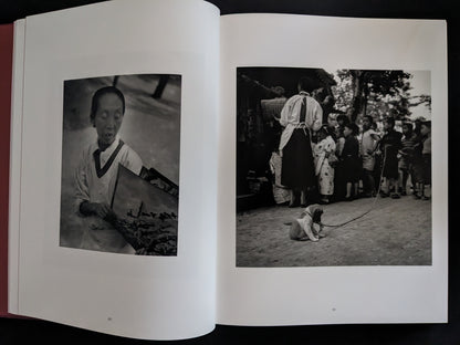 Open book showing black and white photographs of a person and a dog in a traditional setting.