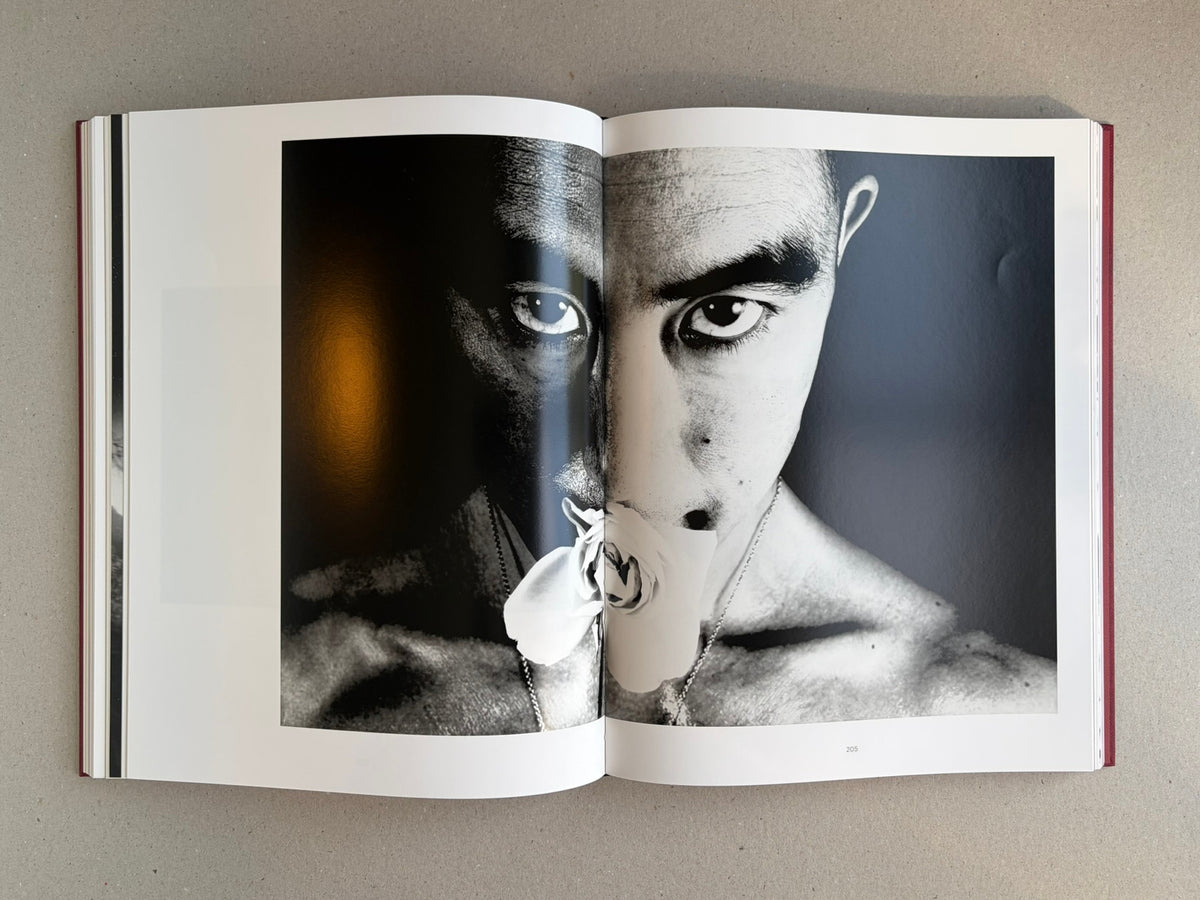 Open spread from Eikoh Hosoe, showing a black-and-white portrait across the gutter with a flower at the mouth and page number 205.