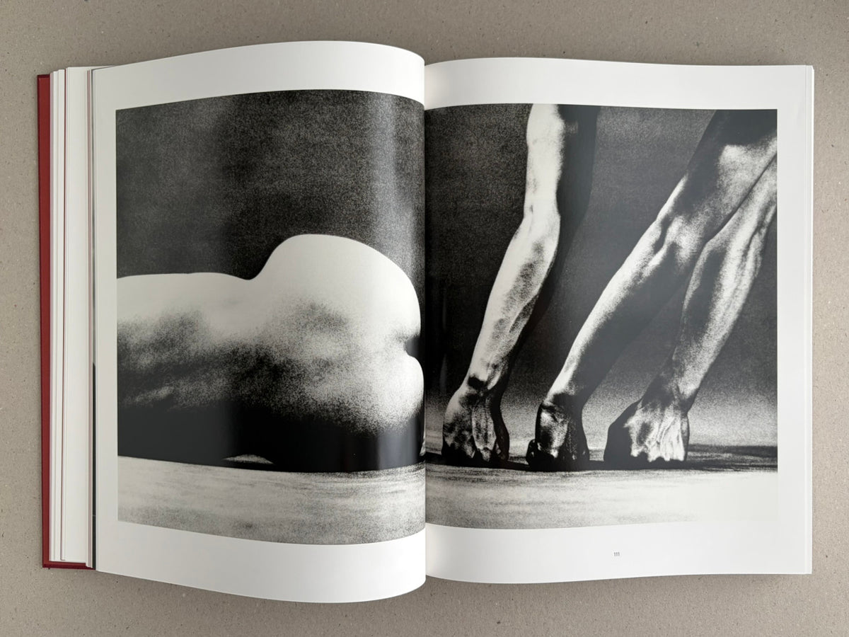 Open spread from Eikoh Hosoe, showing a black-and-white photographic image across two pages with a reclining figure on the left and cropped legs on the right.