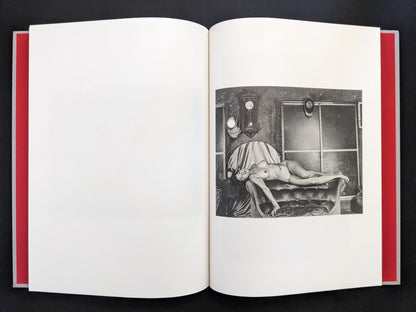 Black and white nude portrait of a woman reclining on a bed in a staged room, from Seiji Kurata’s photobook Eros Lost (1980s work).