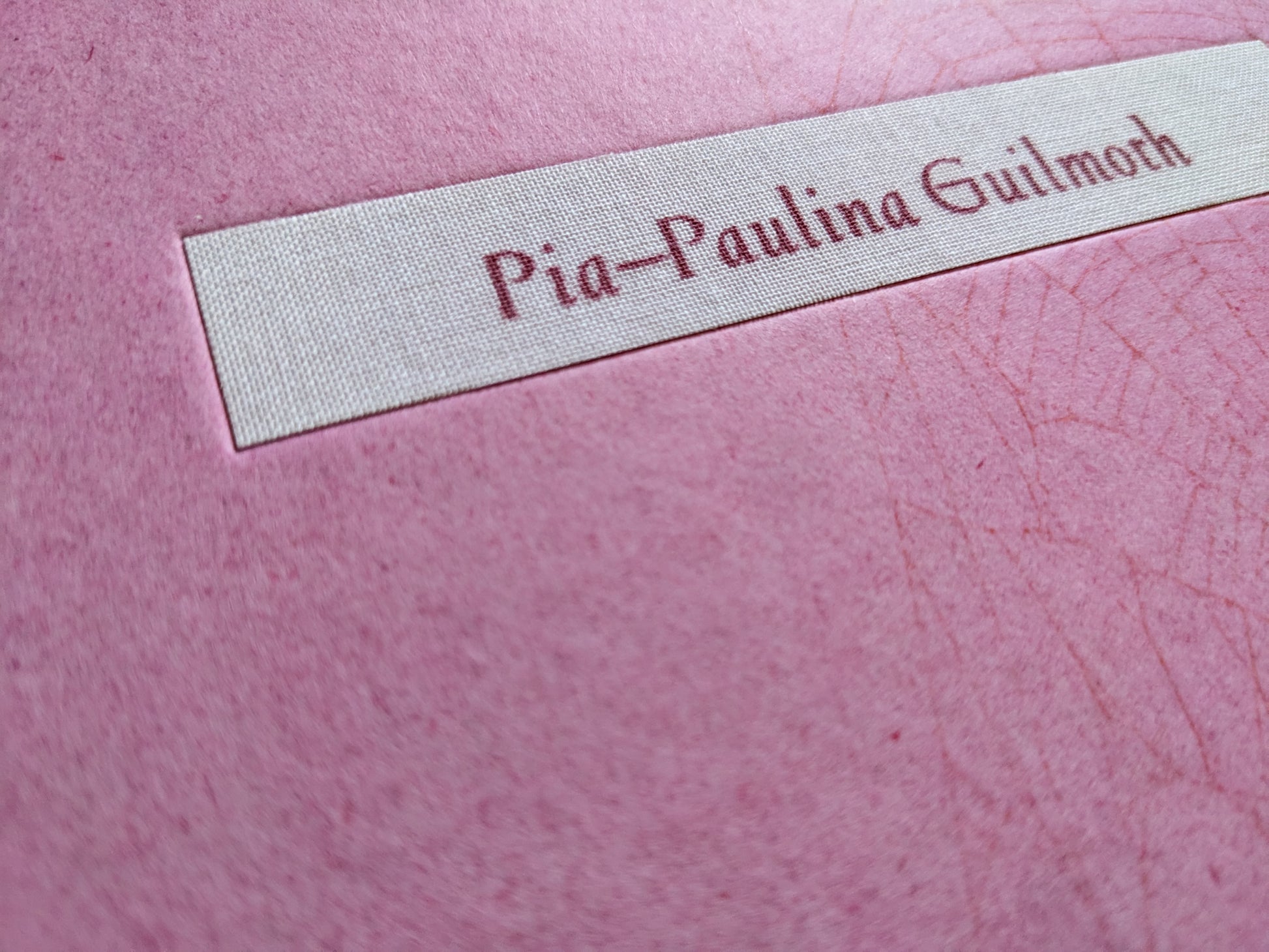 Close-up of the fabric nameplate reading Pia-Paulina Guilmoth on the pink cover.