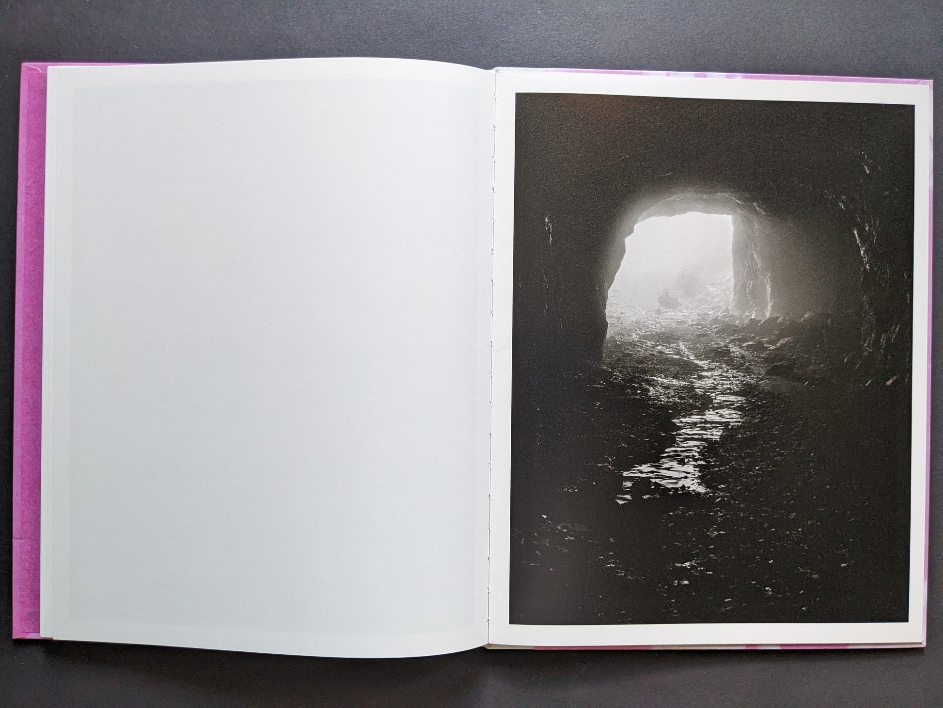 Open spread with a blank left page and a right-hand foggy cave tunnel lit from the far end.