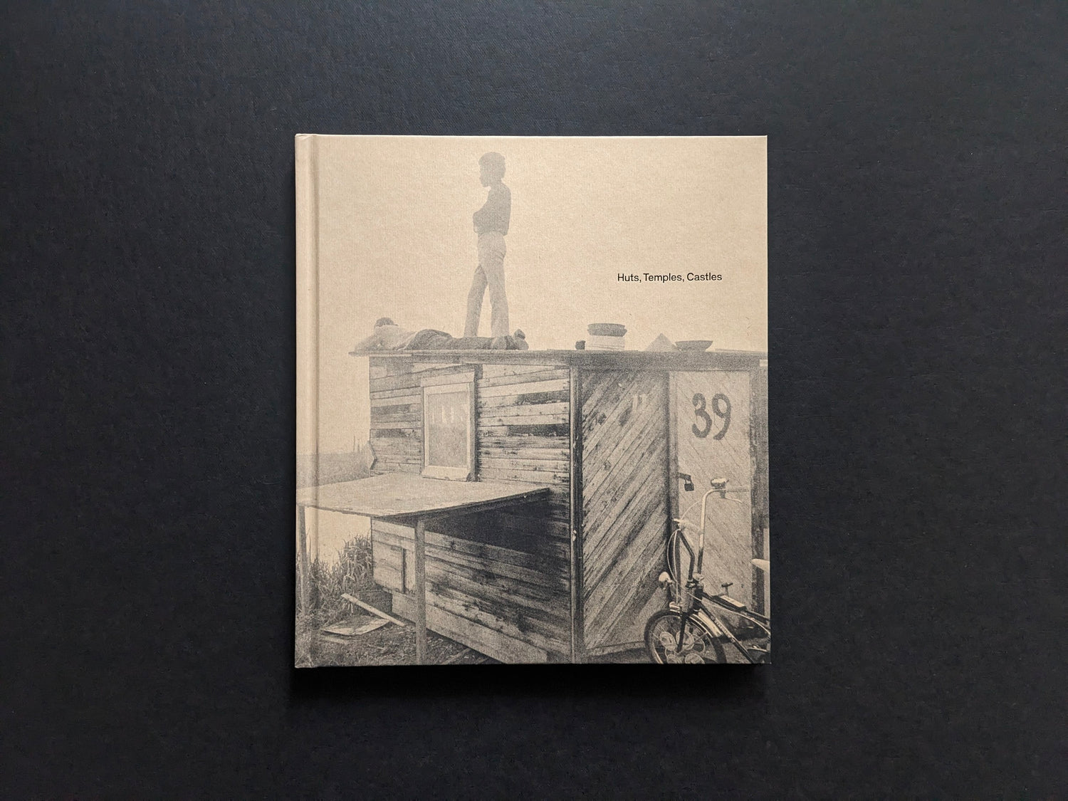 Front cover of Huts, Temples, Castles by Ursula Schulz-Dornburg, showing a child standing on a hand-built hut with the title printed at right.