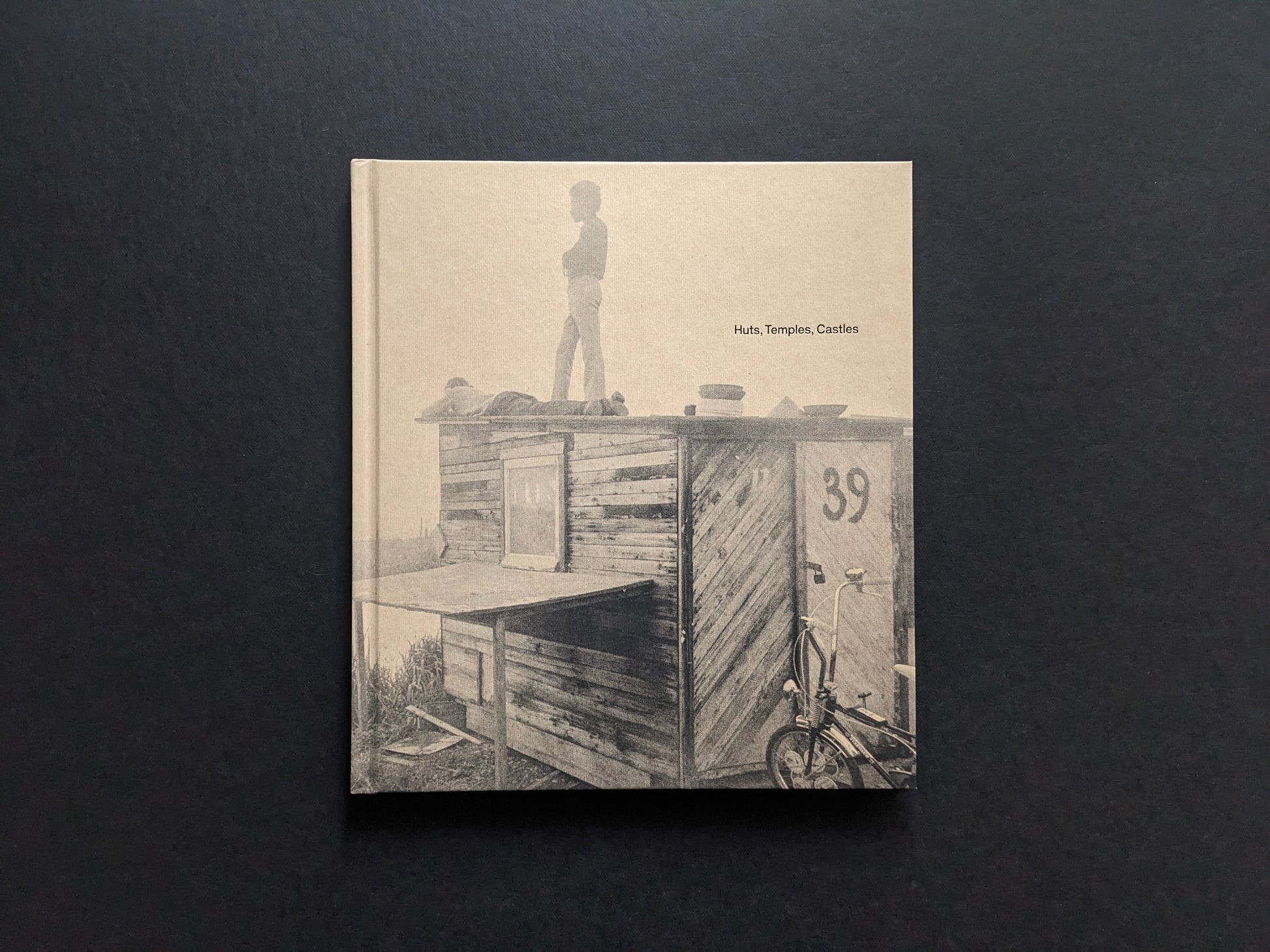 Front cover of Huts, Temples, Castles by Ursula Schulz-Dornburg, showing a child standing on a hand-built hut with the title printed at right.