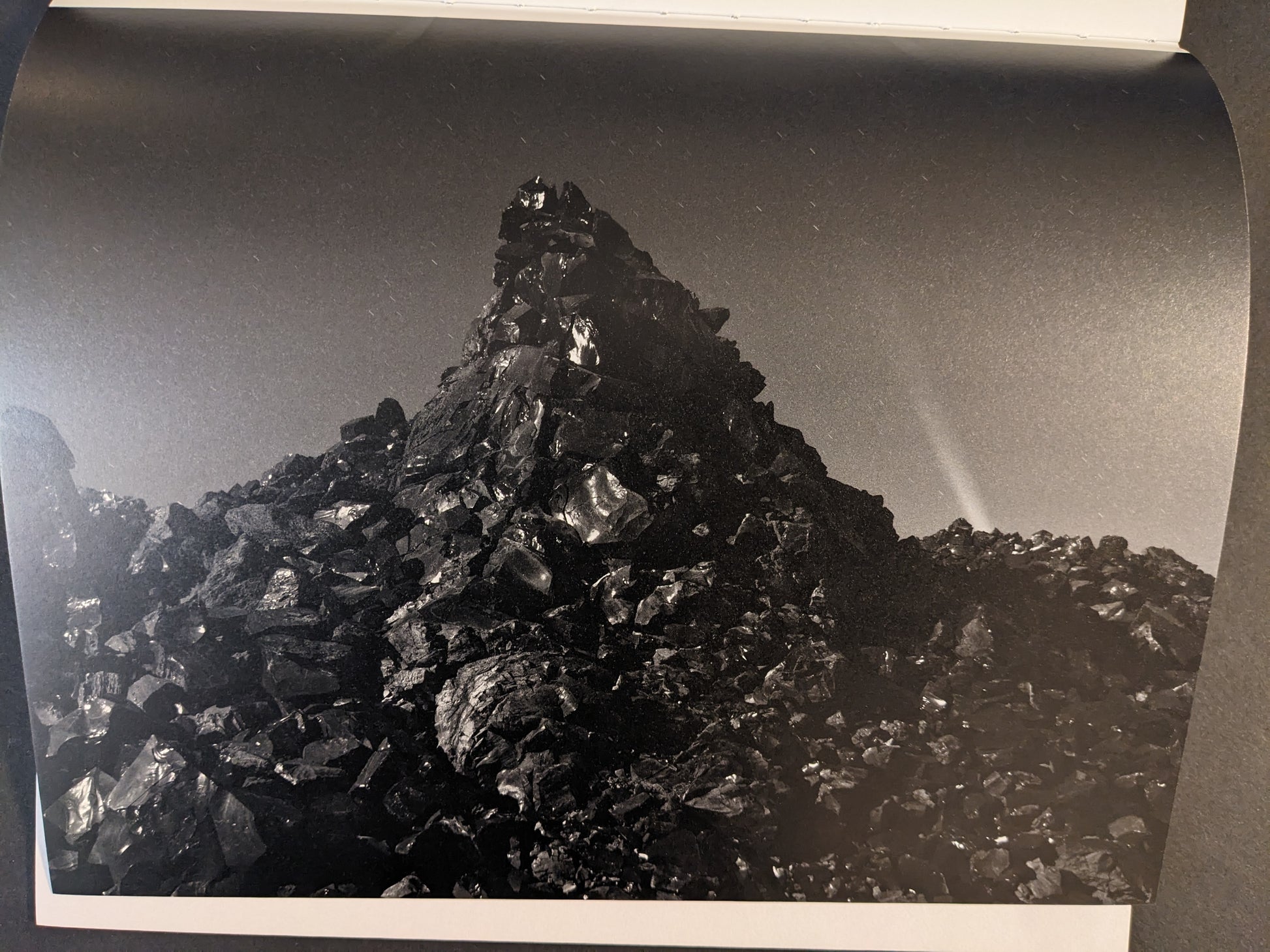 Interior photograph from Glass Mountain by Michael Lundgren, showing a jagged mound of dark rocks under a night sky