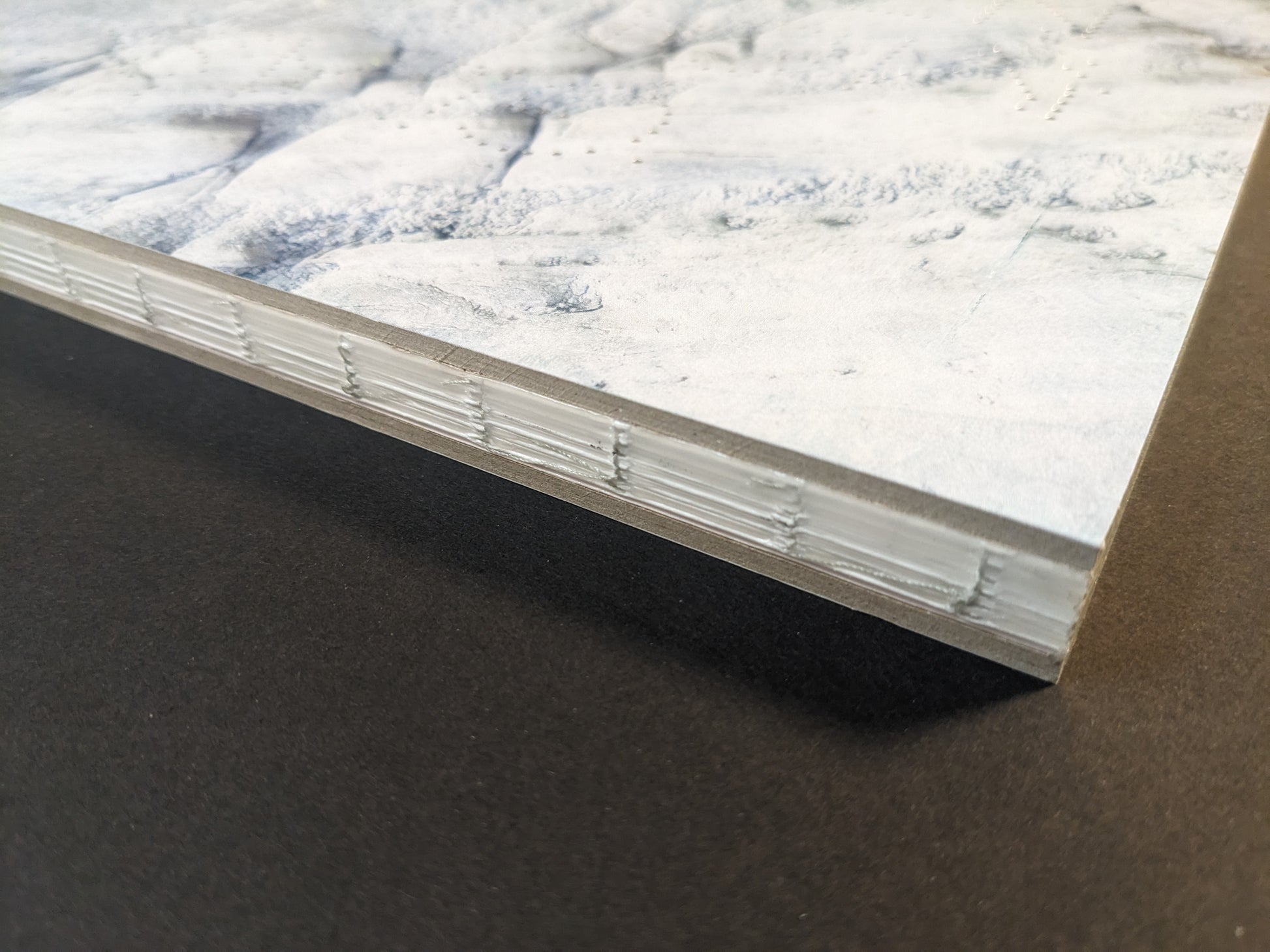 Close-up of Glass Mountain photobook, showing the book block edge and binding detail with chopped boards cover