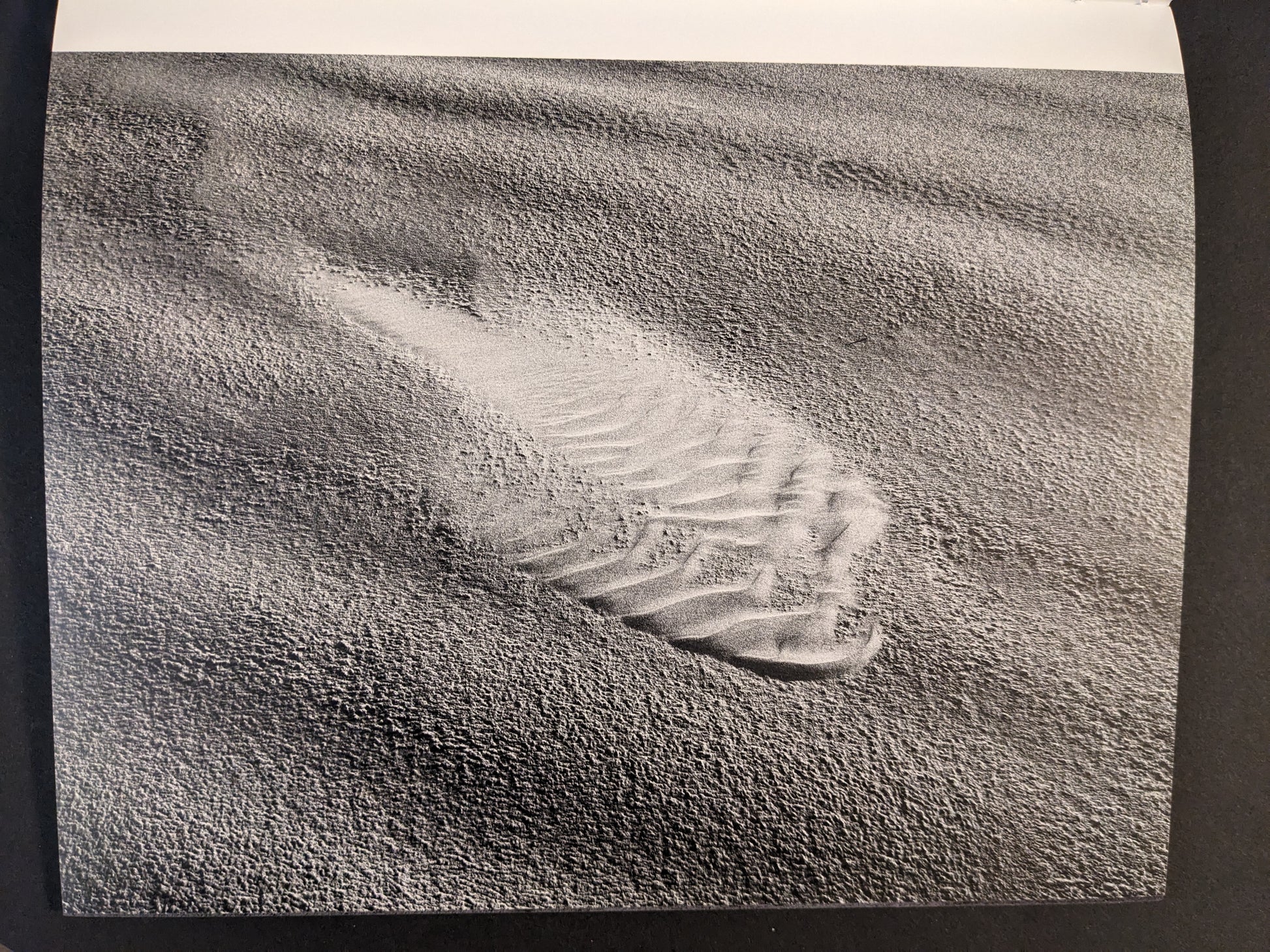 Interior photograph from Glass Mountain by Michael Lundgren, showing a footprint impression in wind-textured sand in black and white