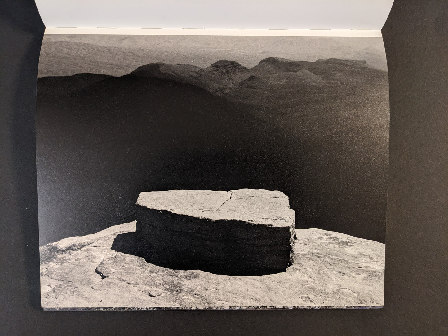 Interior spread from Glass Mountain by Michael Lundgren, showing a black-and-white landscape with a stone slab in the foreground