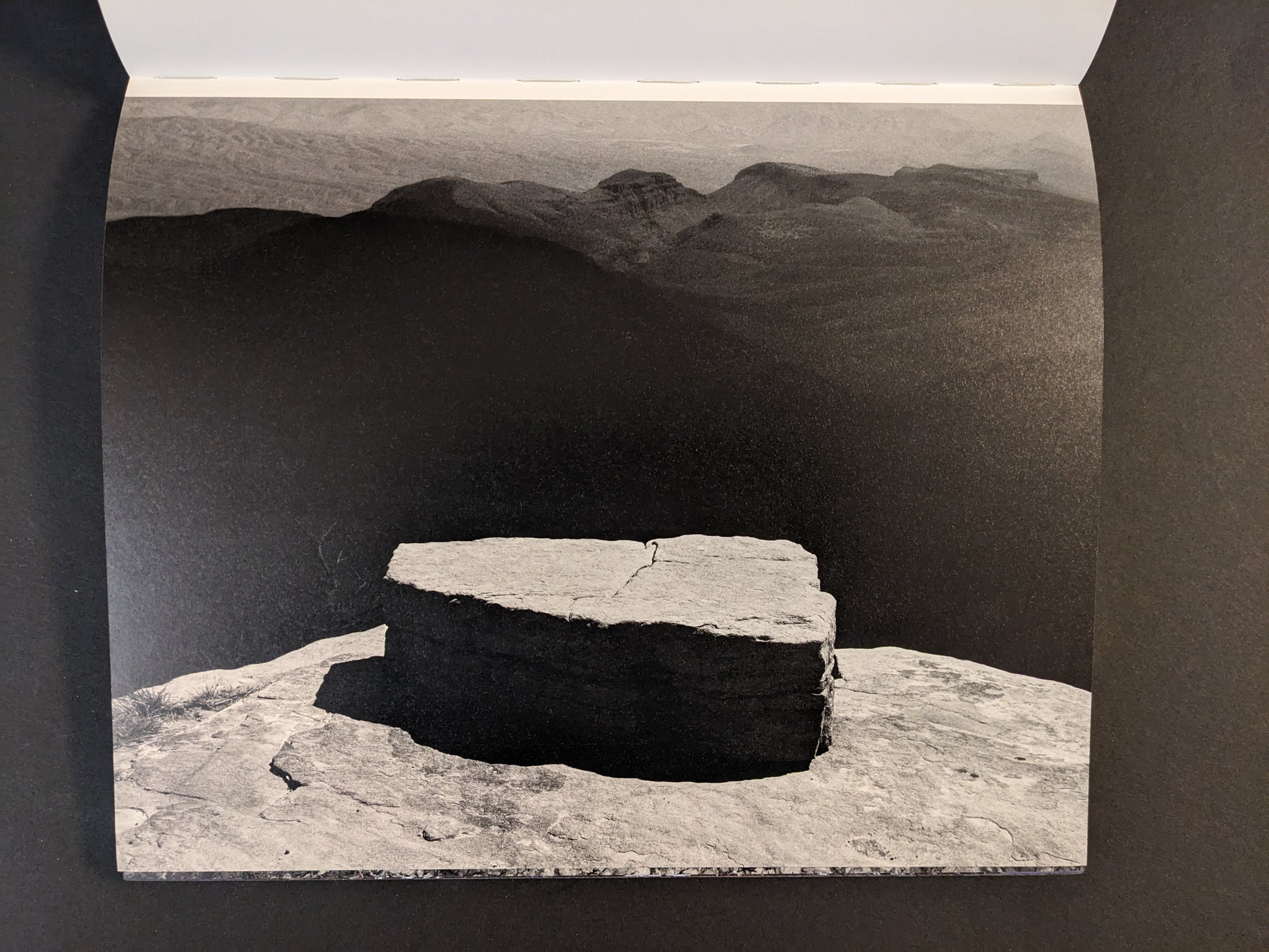 Interior spread from Glass Mountain by Michael Lundgren, showing a black-and-white landscape with a stone slab in the foreground