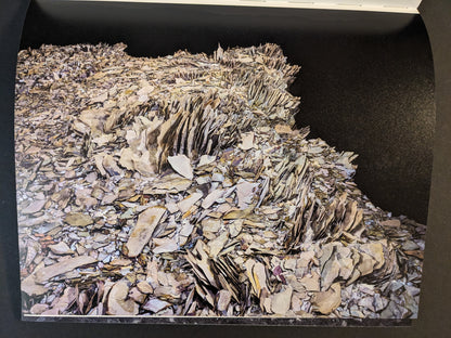 Interior photograph from Glass Mountain by Michael Lundgren showing layered rock plates and fragments against a dark background