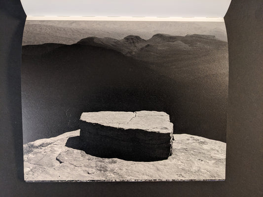Interior spread from Glass Mountain by Michael Lundgren showing a black-and-white landscape with a stone slab in the foreground