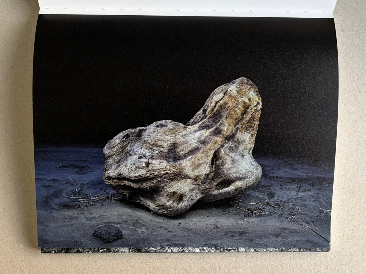 Glass Mountain by Michael Lundgren, open book page showing a single rock on dark ground