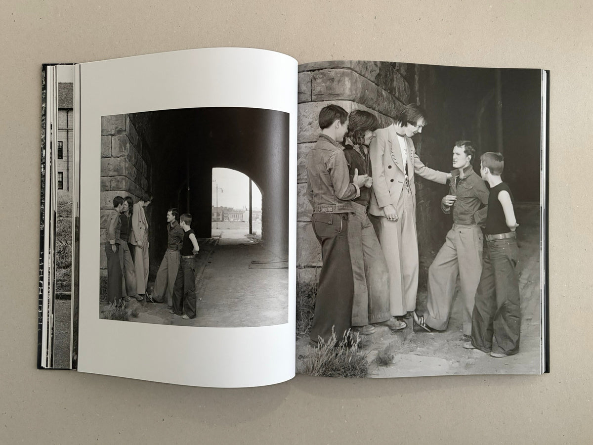 Open book spread from Gorbals by Peter Christopherson, showing two black-and-white photographs of a group of young men standing beneath a stone archway.