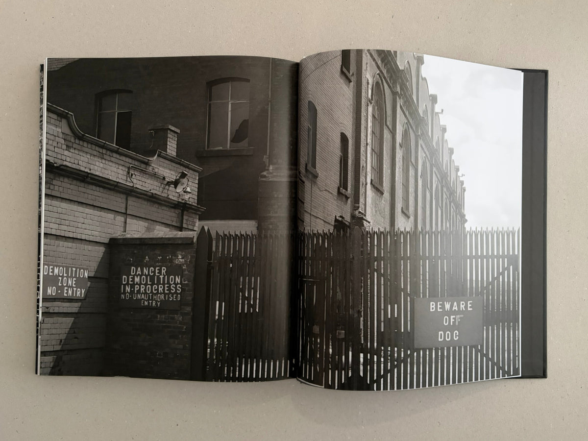 Open photobook spread from Gorbals – Peter Christopherson showing black-and-white urban photographs, with demolition warning signs and a fenced building facade.