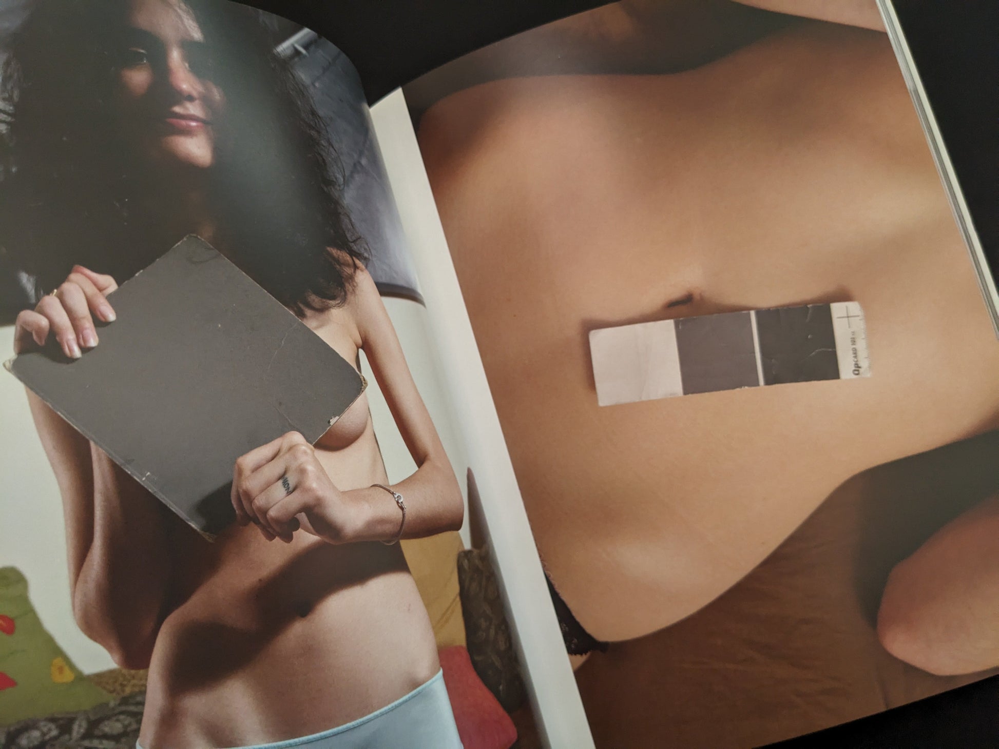 Photo of a nude woman lying down with a grey card placed on her belly from the photobook "Grey Cards" by Richard Kern.