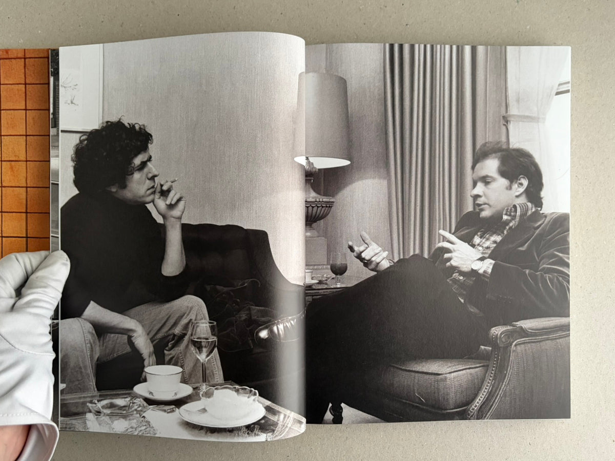 Open spread from HARDCORE (Dust Jacket) by Eric Kroll, showing a black-and-white interior photograph of two men seated and talking in a room.