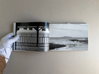 Open spread from Hashima - Taiji Matsue, showing a black-and-white seaside photograph on the left page and a distant island view on the right page.