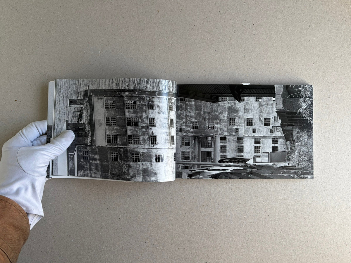 Open spread of Hashima by Taiji Matsue, showing a black-and-white photograph of an abandoned building on the page.