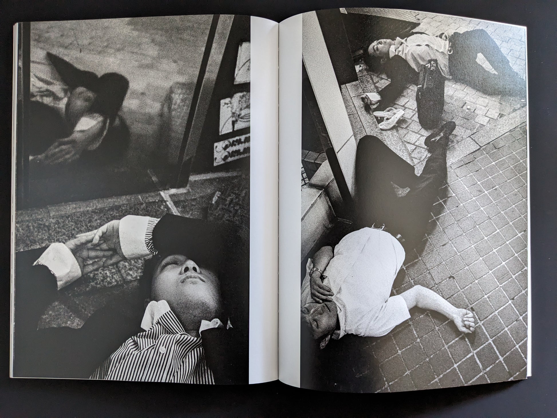 Black and white photo of businessmen lying unconscious in urban Tokyo