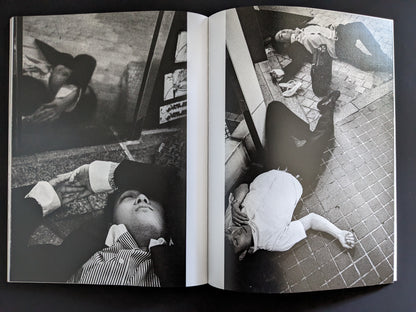 Black and white photo of businessmen lying unconscious in urban Tokyo