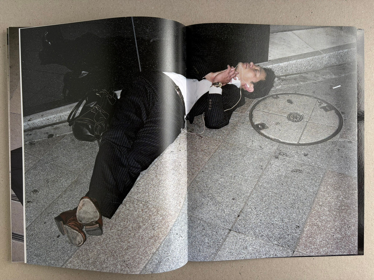 Black-and-white interior spread with a suited man lying on the ground, photographed from above.