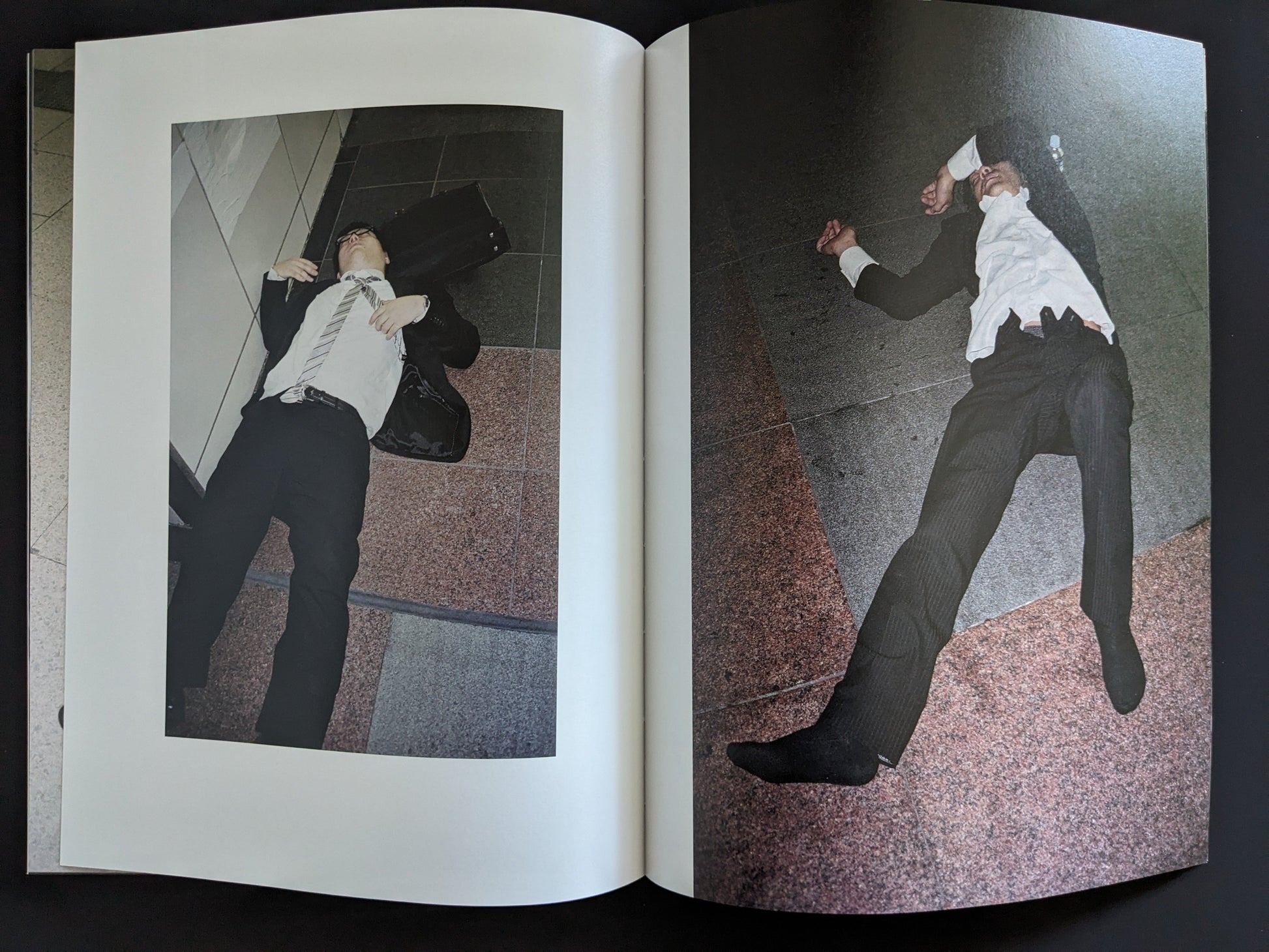 Open spread of two men passed out on an indoor checkered tile floor in business suits