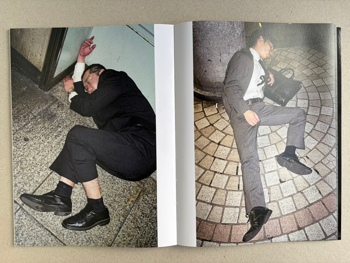 Interior spread with two colour photographs of sleeping suited men on pavement and steps.