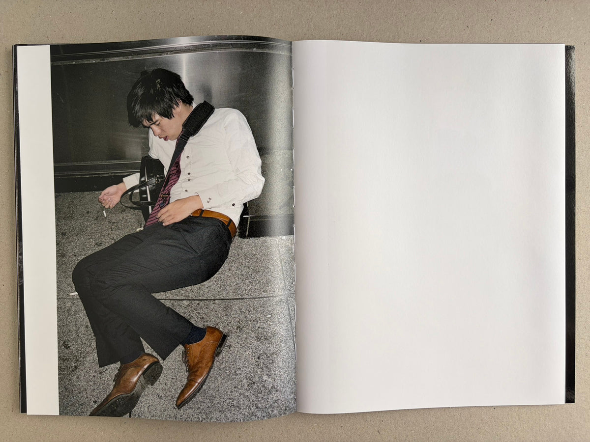 Interior spread with a colour portrait of a suited man slumped on the left page and a blank right page.