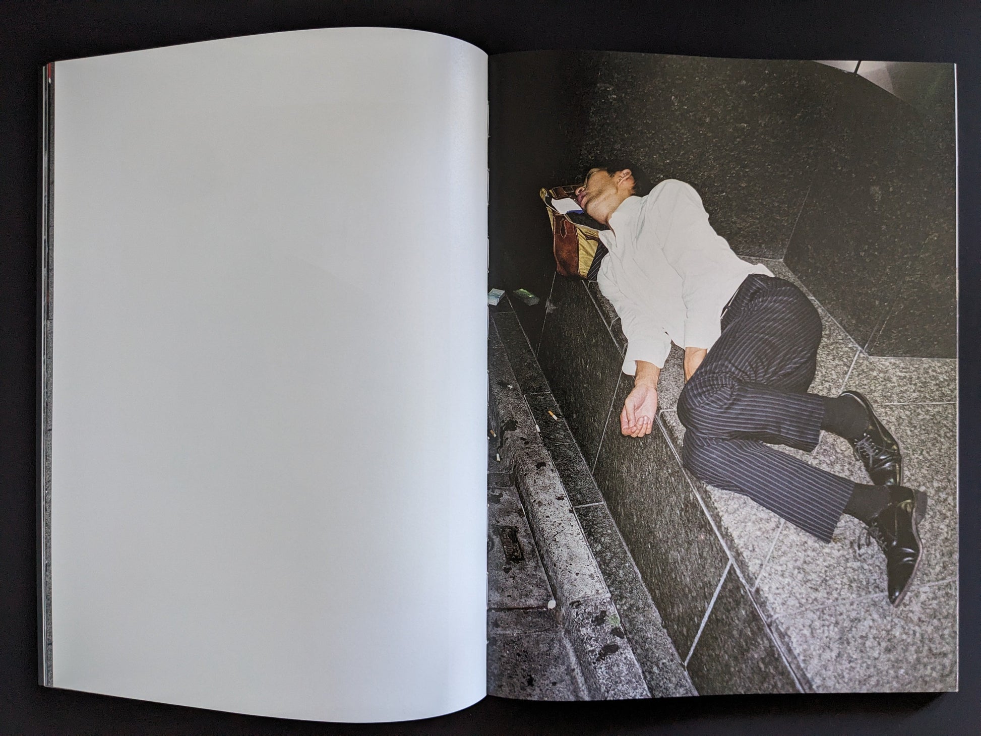 Open spread with a businessman asleep on a stone bench and a blank page opposite