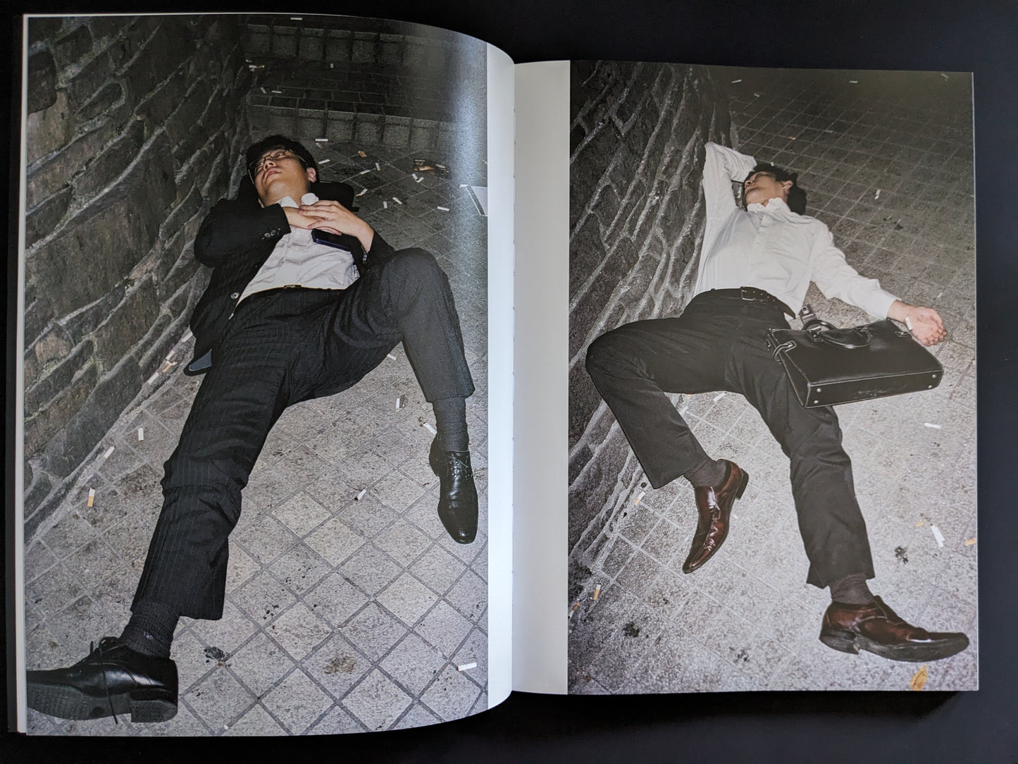 Open spread showing two men in business attire lying on a sidewalk at night