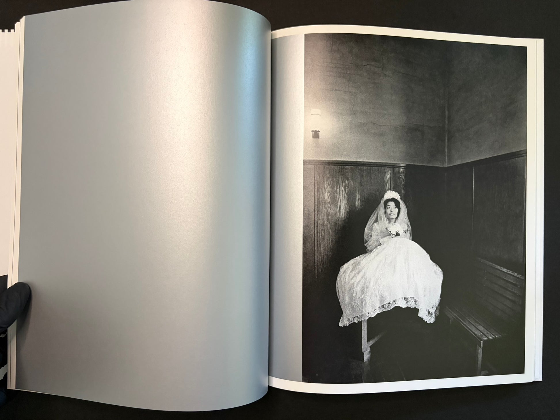 Open spread with a bride seated on a bench on the right page and a blank left page
