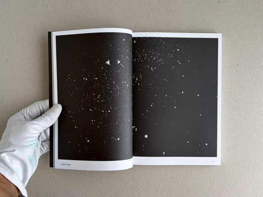 Open spread from Hotshoe Issue 209: An Emotional Landscape, showing a dark two-page image with scattered white specks and a gloved hand holding the magazine.