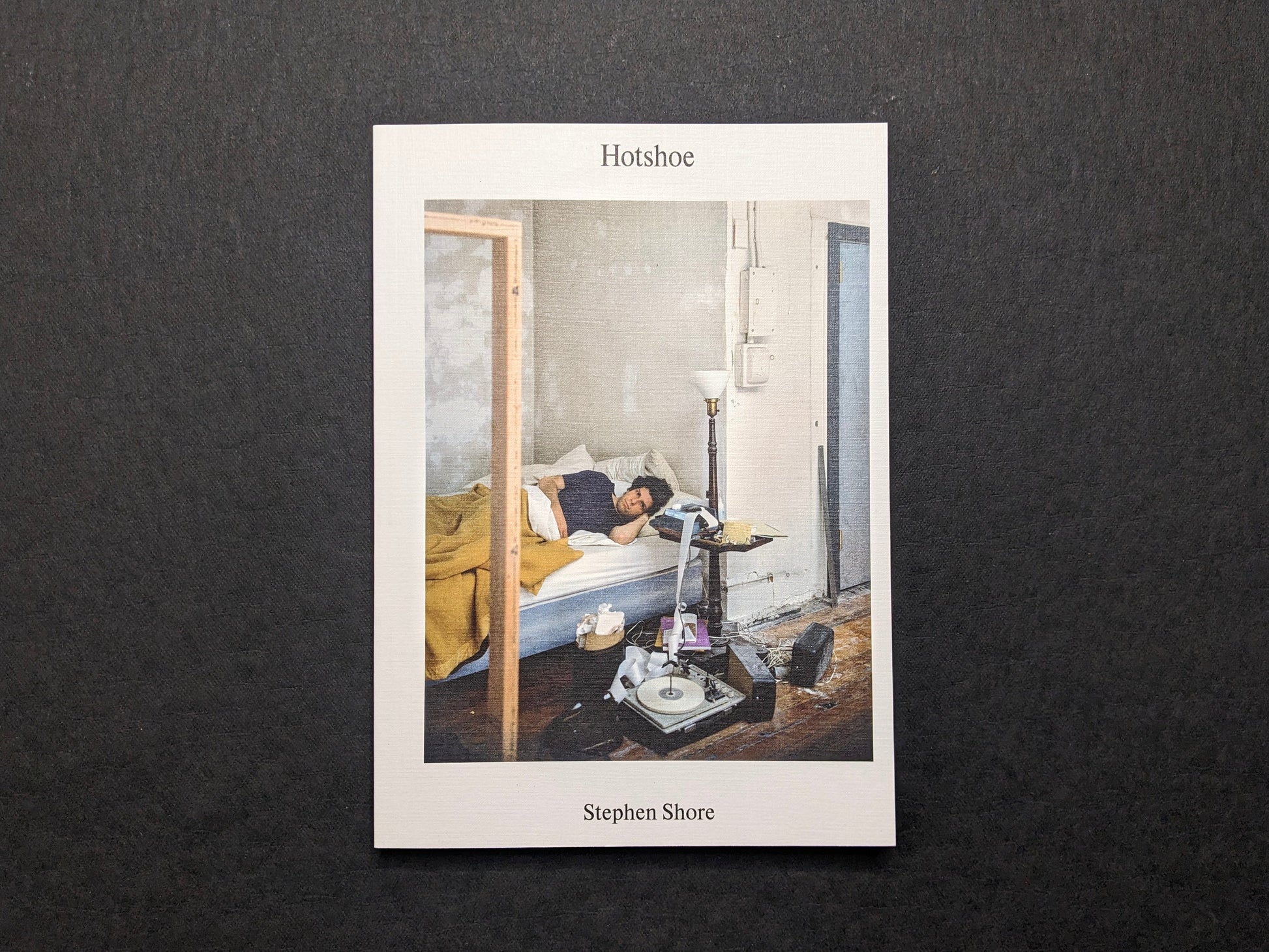 Cover of Hotshoe Issue 214 featuring a color photograph by Stephen Shore of a man lying on a bed in a sparse room.