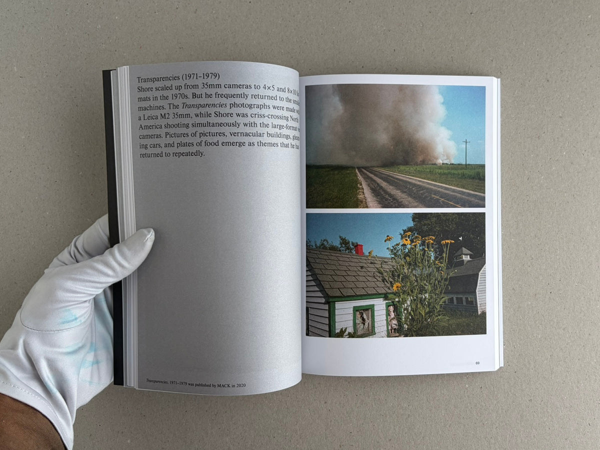 Open Hotshoe Issue 214: Stephen Shore showing a spread with text on the left page and two colour photographs on the right page, held open by a gloved hand.