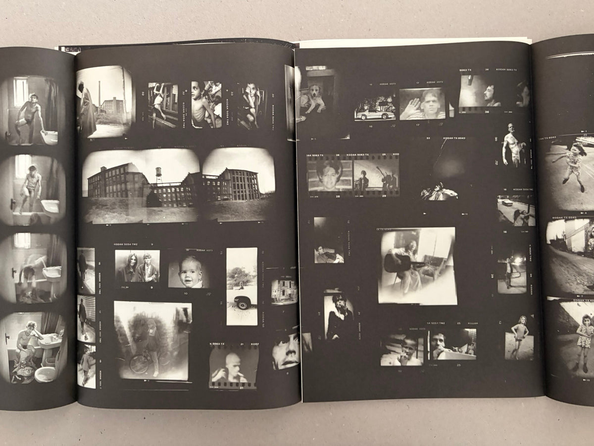 Open spread from Hunger: Epilogue (2nd Ed.) by Michael Ackerman, showing a black-and-white layout of many small photographs on dark pages.