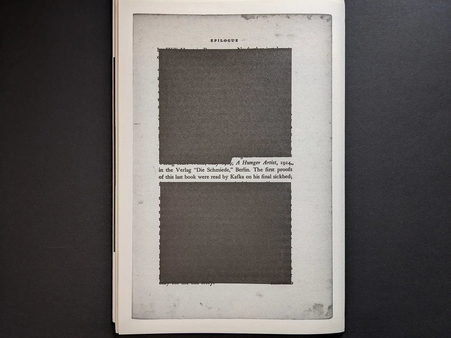 Epilogue page from Hunger – Epilogue showing a framed text layout with two large dark redacted rectangles over Kafka-related text.