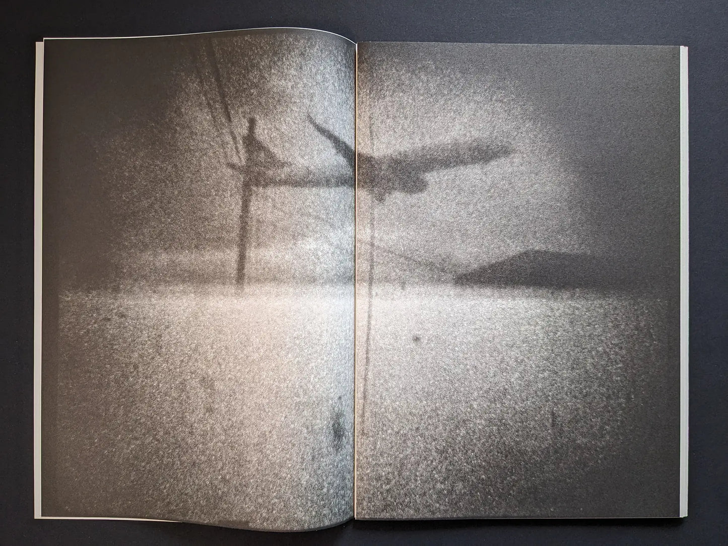 Interior spread from Hunger – Epilogue showing a grainy black-and-white scene of a low flying plane over water and distant land.