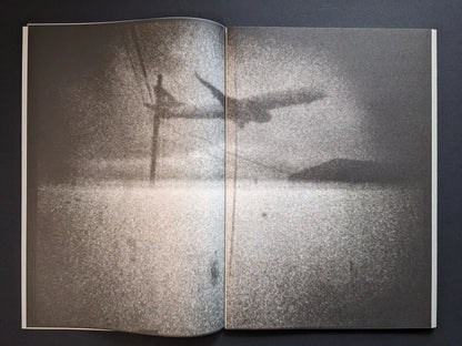 Interior spread from Hunger – Epilogue showing a grainy black-and-white scene of a low flying plane over water and distant land.