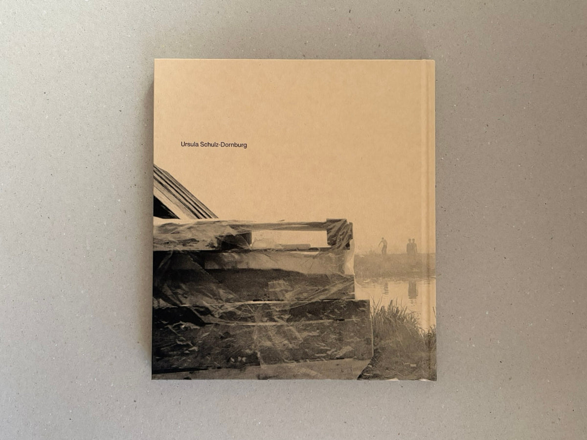 Cover of Huts, Temples, Castles by Ursula Schulz-Dornburg, showing a beige hardcover with the artist’s name and a photograph of a makeshift structure by water.