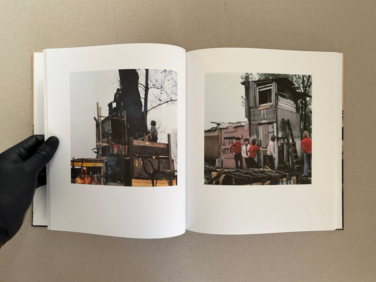 Open spread of Huts, Temples, Castles by Ursula Schulz-Dornburg, showing two colour photographs of improvised wooden structures and children at Jongensland.
