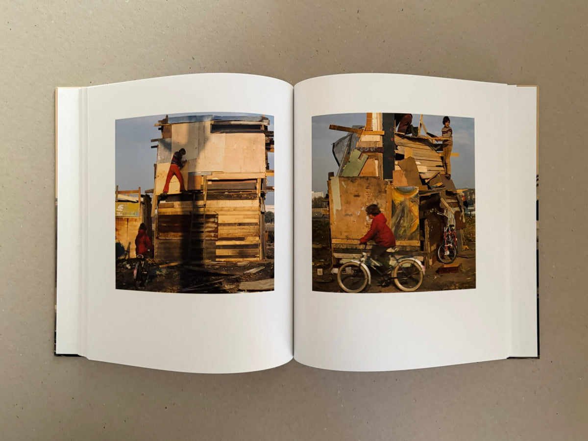 Open spread of Huts, Temples, Castles by Ursula Schulz-Dornburg, showing two colour photographs of a makeshift wooden structure with children around it.