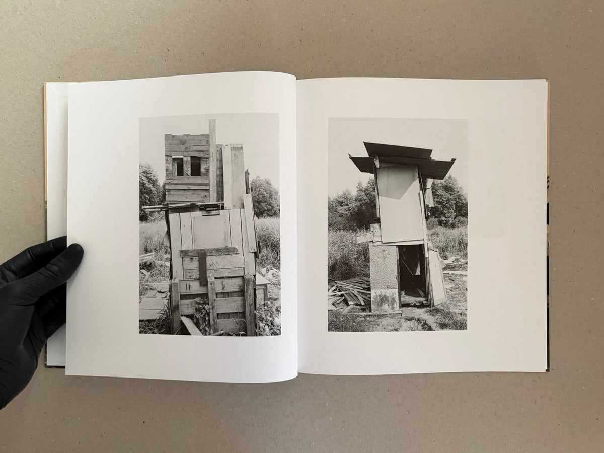 Open spread of Huts, Temples, Castles by Ursula Schulz-Dornburg, showing two black-and-white photographs of improvised wooden structures on facing pages.