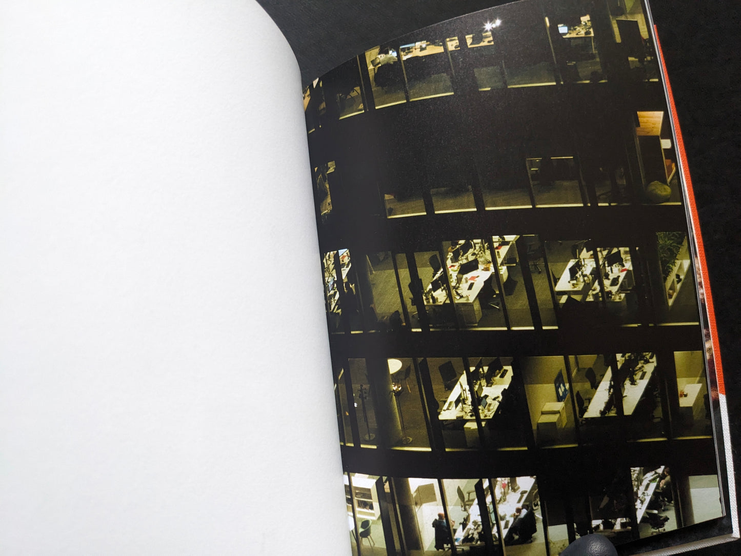 Night view of a building with lit office windows, from I’ll Bet The Devil My Head by Carlos Alba.
