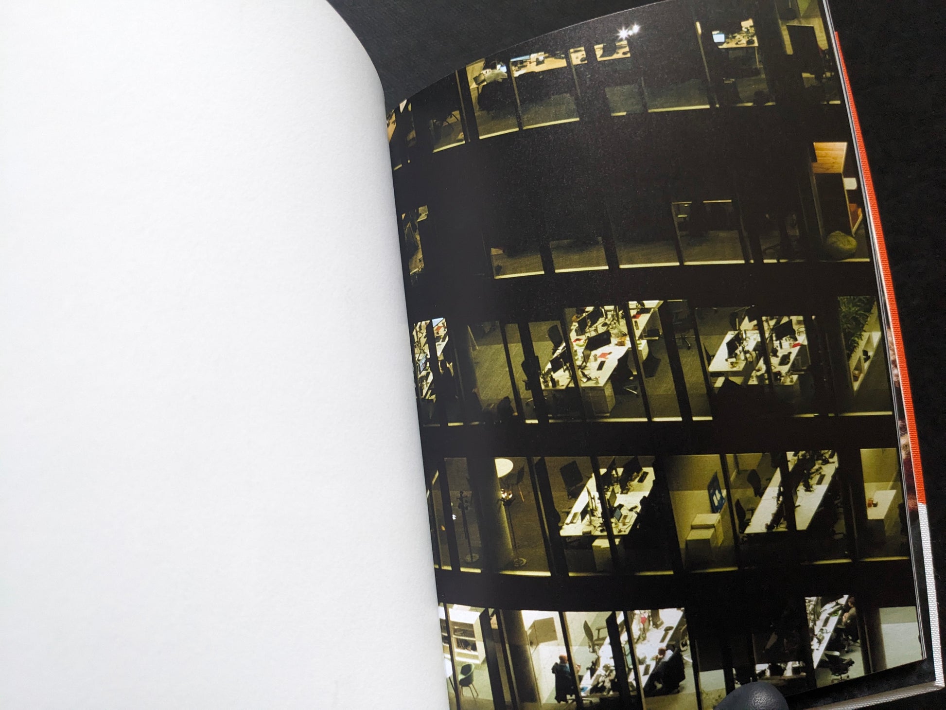Night view of a building with lit office windows, from I’ll Bet The Devil My Head by Carlos Alba.