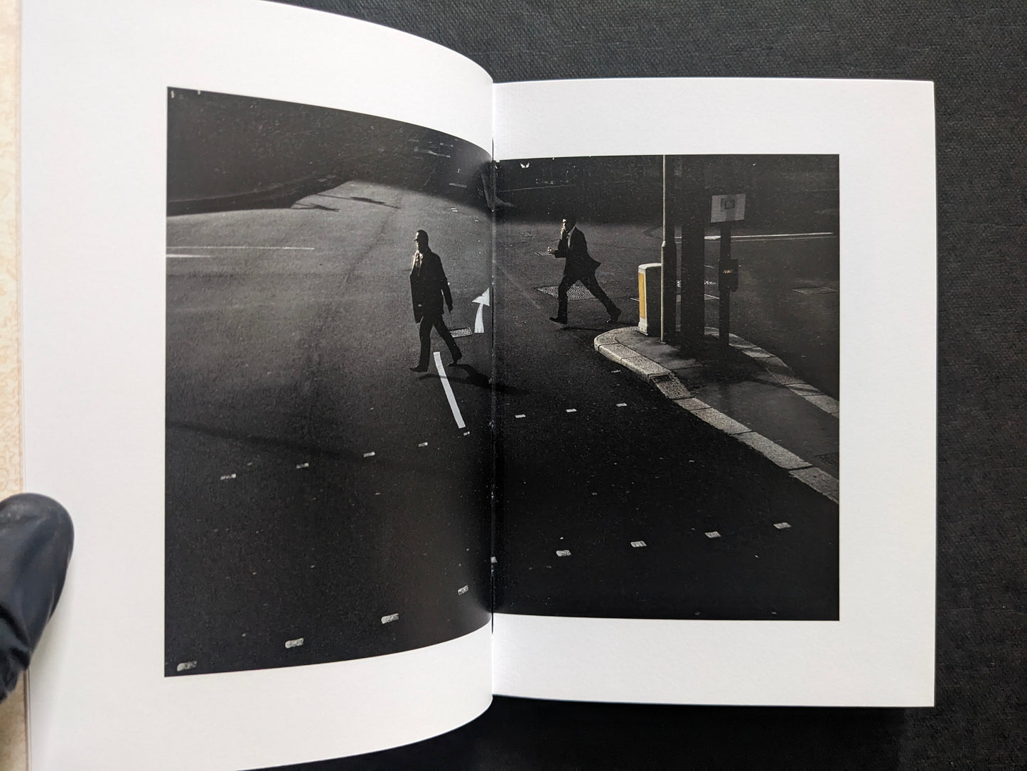 Book spread showing a dark street scene with two men crossing an empty road.