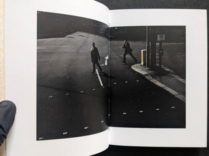 Book spread showing a dark street scene with two men crossing an empty road.