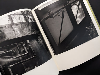 Industrial pipes and mechanical window opener inside a greenhouse, photographed in black and white by Takeshi Shinoda.